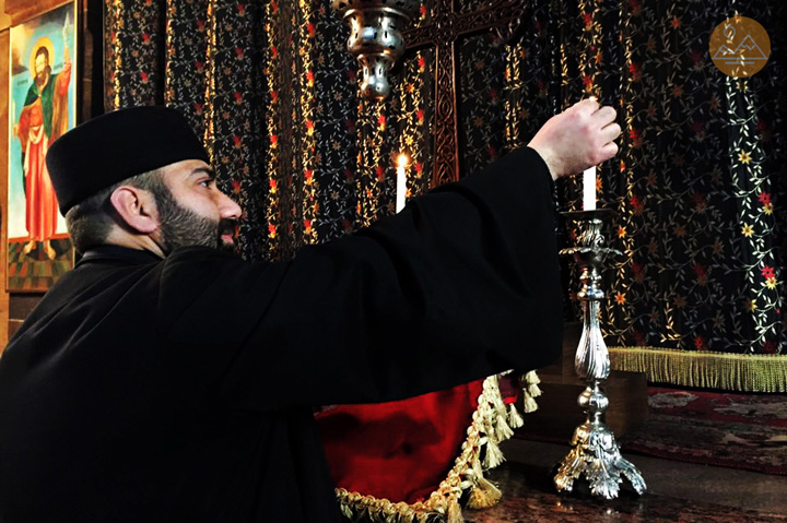 Armenian priest lights candles in a church